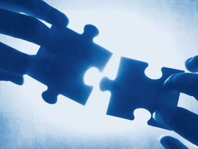 hands trying to fit two puzzle pieces together